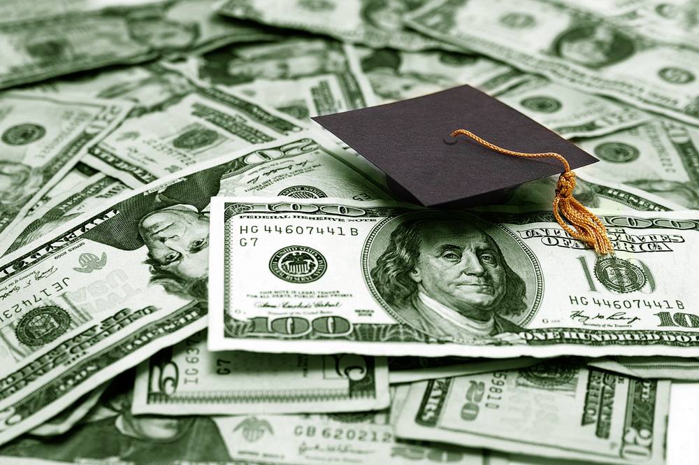 graduation cap on a pile of money