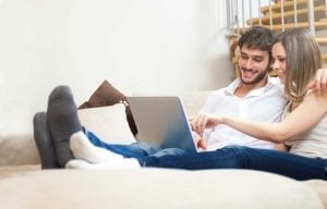 Couple on couch looking at computer and smiling