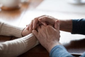 Hands clasped together in support of cancer patient