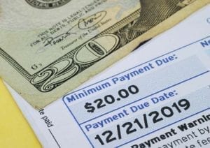 Bill to pay the minimum payment on credit card debt on table with money
