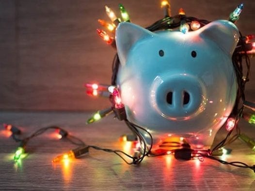 How to Stay Out of Debt During the Holidays Piggy bank wrapped in Christmas lights