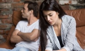 Younger stressed couple discussing relationship issues on sofa