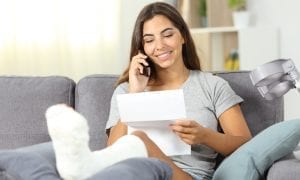 Disabled woman on the phone reading a letter sitting on a couch in the living room at home