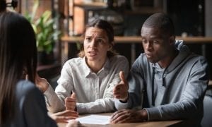 Younger dissatisfied couple disputing their debt with a representative