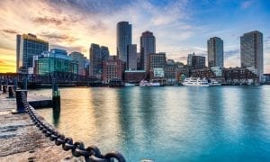 Photo of Boston harbor waterfront with downtown Boston skyline in background near sunset