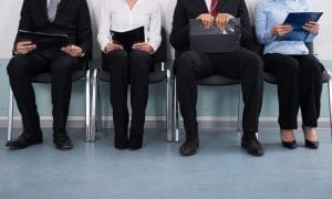 Photo of business people sitting in lobby with files in hand waiting for interview
