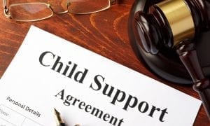 Child support agreement form on judges desk next to glasses and gavel