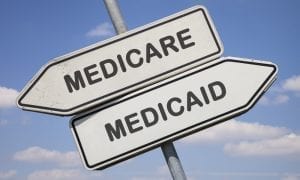 Two white direction signs with arrows and the words medicare and medicaid