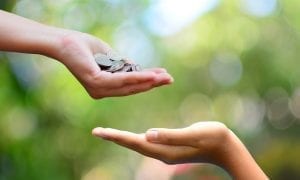 One persons hand giving money to other persons hand