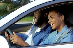 Teenager driving a car with his dad