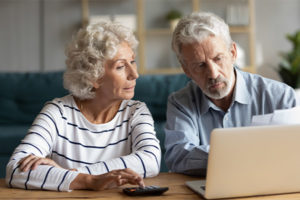 Senior couple researching their debt consolidation options on the computer