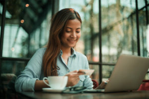 Young woman at a coffee shop holding a new credit card to build credit