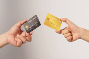 Two credit cards being held by people.