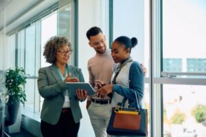 Happy real estate agent using digital tablet with her clients during consultations in the office.