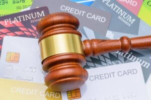 A wooden gavel placed on top of many credit cards.