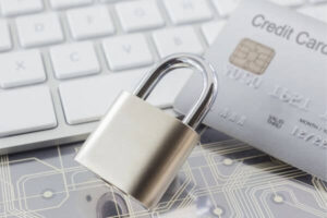 Padlock and credit card on keyboard and electronic circuits.