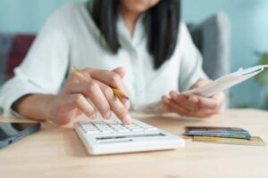 Hand of woman with a calculator and credit cards portraying tax concept.