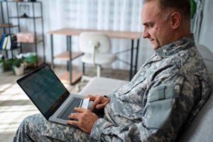 Veteran using laptop and credit card representing financial help options.