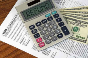 Calculator with refund text sign on 1040 income tax form and American hundred dollar bills