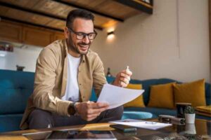 Man reviewing paperwork at home and smiling after receiving a tax refund.